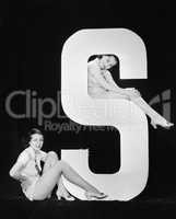 Women posing with huge letter S