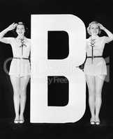 Two women saluting with huge letter B