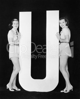 Women posing with huge letter U