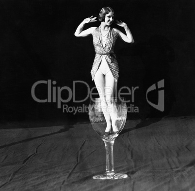 Tiny woman standing in wineglass