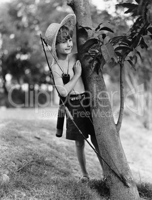 Boy behind tree with bow and arrow