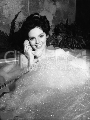 Woman talking on phone in bubble bath