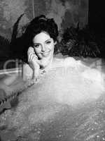 Woman talking on phone in bubble bath