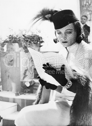 Woman in hat and veil reading sheet music