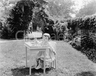 Toddler eating at table in garden