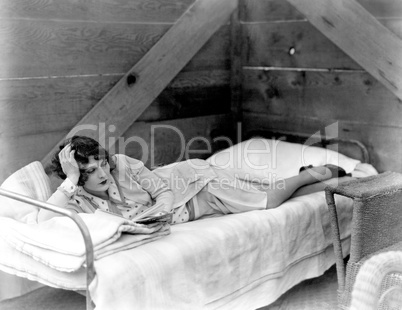 Woman lying on cot reading