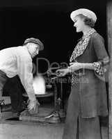 Woman with man at foundry weighing silver
