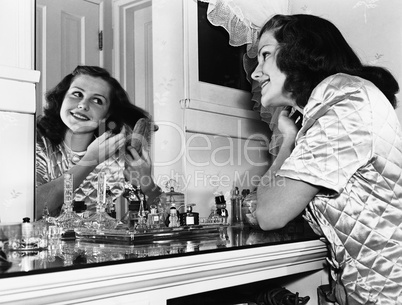 Young woman brushing hair at dressing table