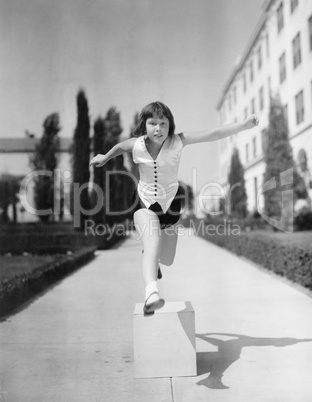 Girl leaping over wooden blocks