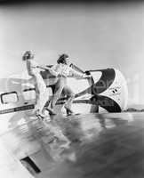 Two women walking on the wing of a plane