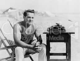 Man sitting at the beach with his typewriter