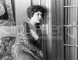 Young woman leaning against the wall, looking sad