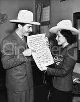 Couple with cowboy hats looking at sheet music