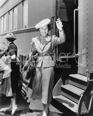 Young woman next to train waving