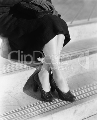 Young woman's legs in high heels sitting on a step