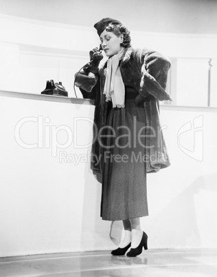 Young woman leaning on a counter and talking on the telephone