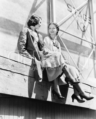 Two women sitting together on scaffolding