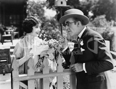Man and woman talking over a picket fence