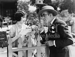 Man and woman talking over a picket fence