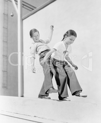 Boy and girl trying to balance on a ledge