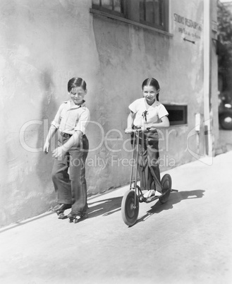 Boy and girl playing on a scooter and the other on roller blades