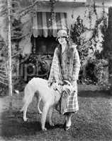 Young woman in coat and hat standing outside with her Russian Wolfhound