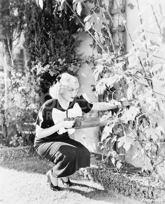 Young woman with a big saw trying to cut flowers