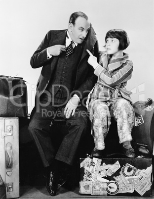 Father and daughter sitting together on luggage