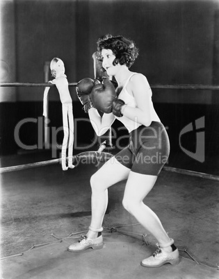 Young woman with boxing gloves with a doll on the ropes