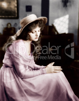 Young woman in a hat sitting and looking sad