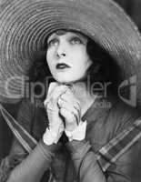 Young woman praying in a big hat