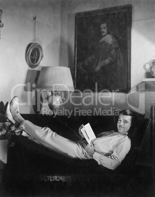 Man sitting on a couch reading a book