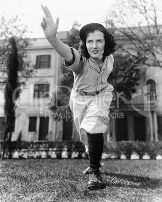 Young woman in baseball uniform throwing a ball