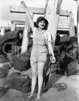 With sand between her toes, a young woman waves on the beach