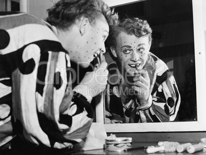 Man in front of a mirror putting make up on