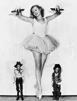 Young woman in a ballerina tutu keeps on her toes to control the men at her feet