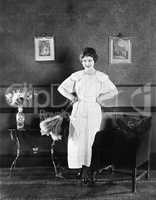 Young woman in an apron and a duster standing in a living room
