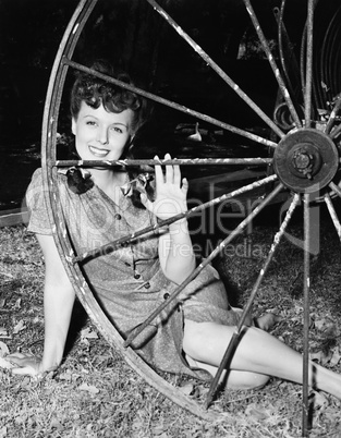 Young woman smiling while sitting behind a wagon wheel
