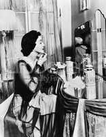 Young woman looking into a mirror and putting on make up