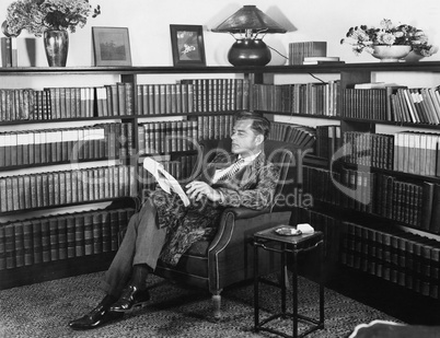 Man sitting in his library reading a book