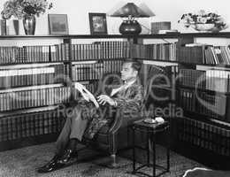 Man sitting in his library reading a book