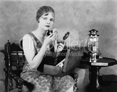 Young woman looking into a mirror and putting on make up