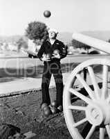Man in sailors uniform trying to juggle cannon balls