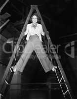Young woman climbs a ladder to the top
