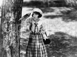 Dressed to kill, a young woman with a knife waits behind a tree