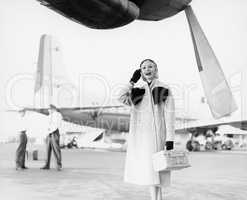 Young woman standing next to an airplane looking happy