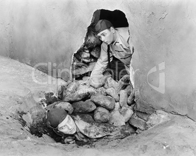 Two men crawling out of a hole in a wall