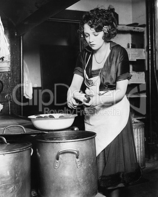 Woman in a kitchen peeling potatoes