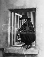Woman as Zorro crouching in a window