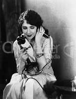Young woman sitting on a chair talking on the telephone